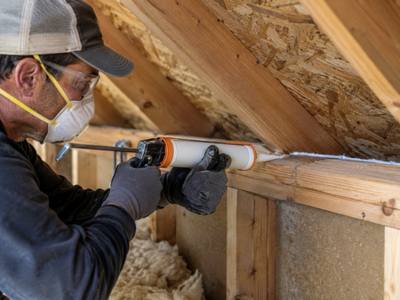 Caulking gun sealing the gap along a top plate before insulating an Innisfil attic