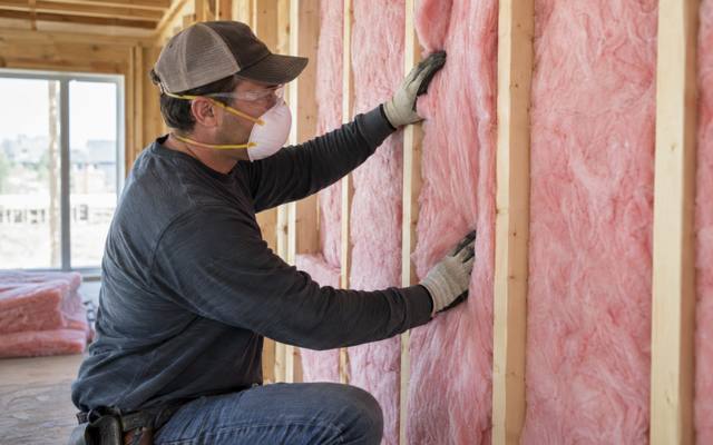 Fiberglass batt insulation being fitted into a framed wall in an Innisfil house