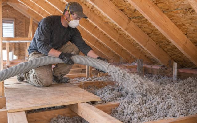 Blown-in cellulose insulation being spread across attic joists in Innisfil